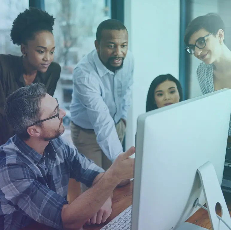 Diverse engineering team collaborating at a computer, reviewing work together in a focused office environment.
